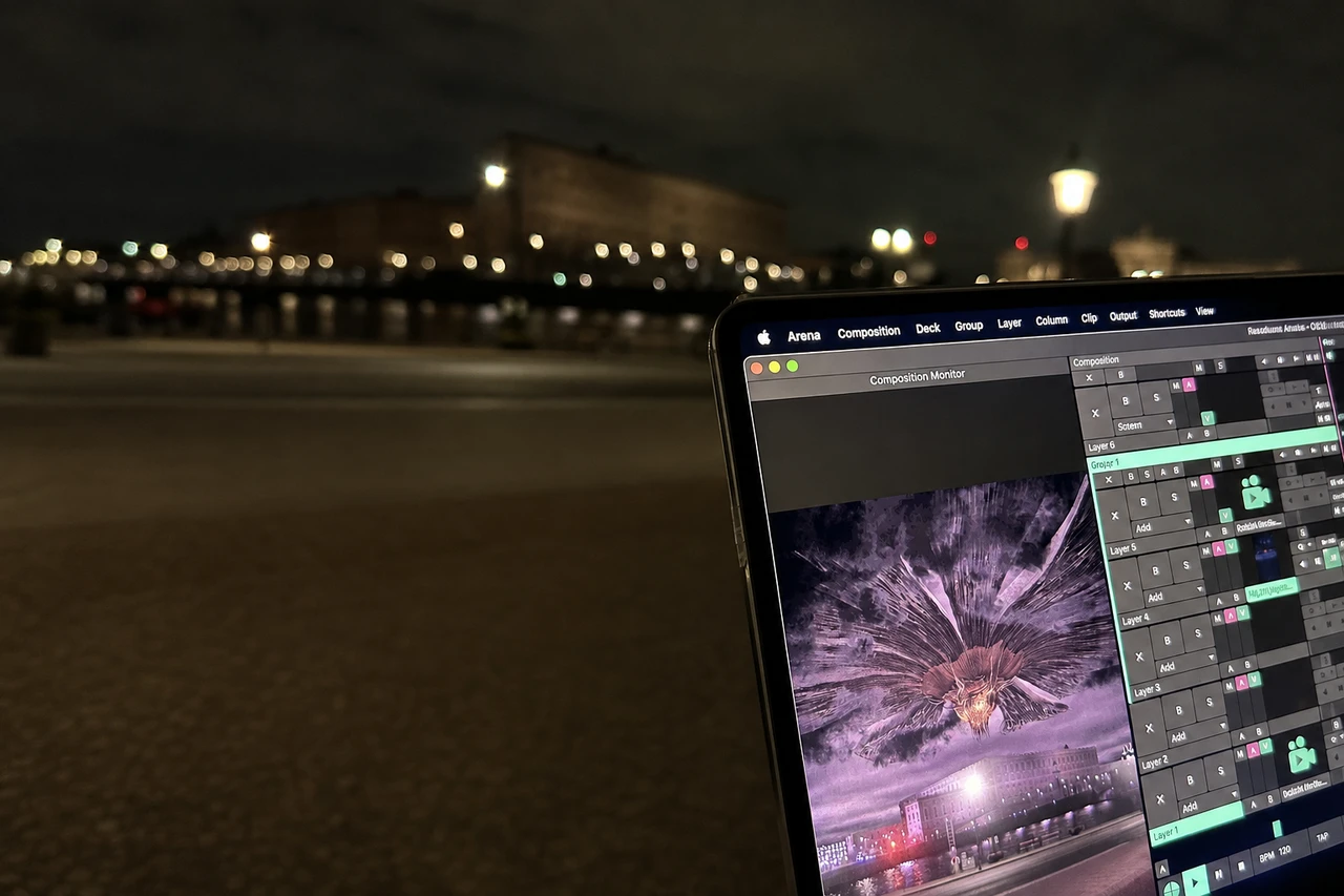 A laptop running the alien invasion scene in Resolume overlooks the softly lit Stockholm waterfront at night.