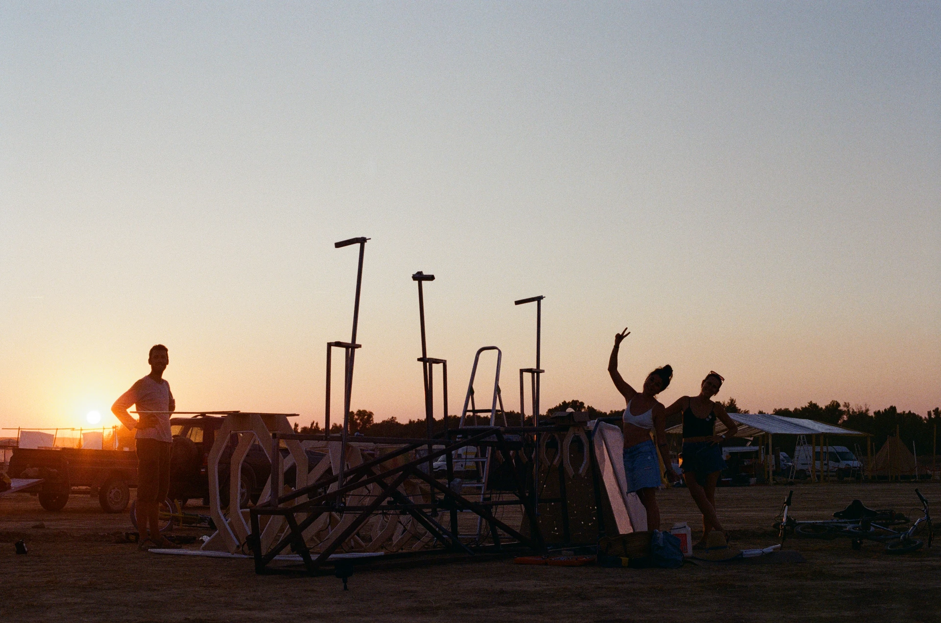 A film photograph of three crew members beside the whale's unfinished frame at sunset, with one raising a peace sign.