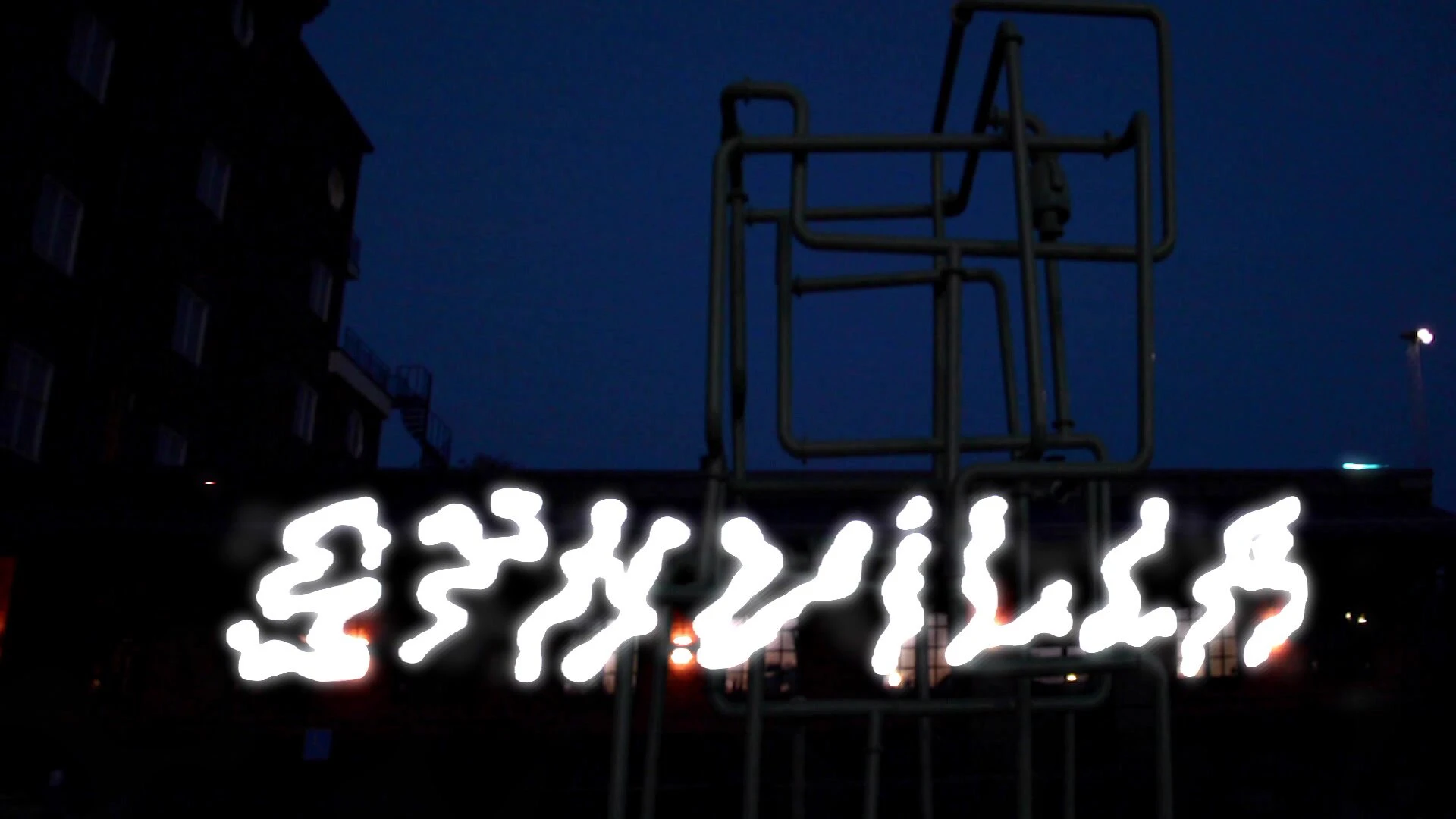 Synvilla in jagged light letters beneath a tall metal frame at dusk.