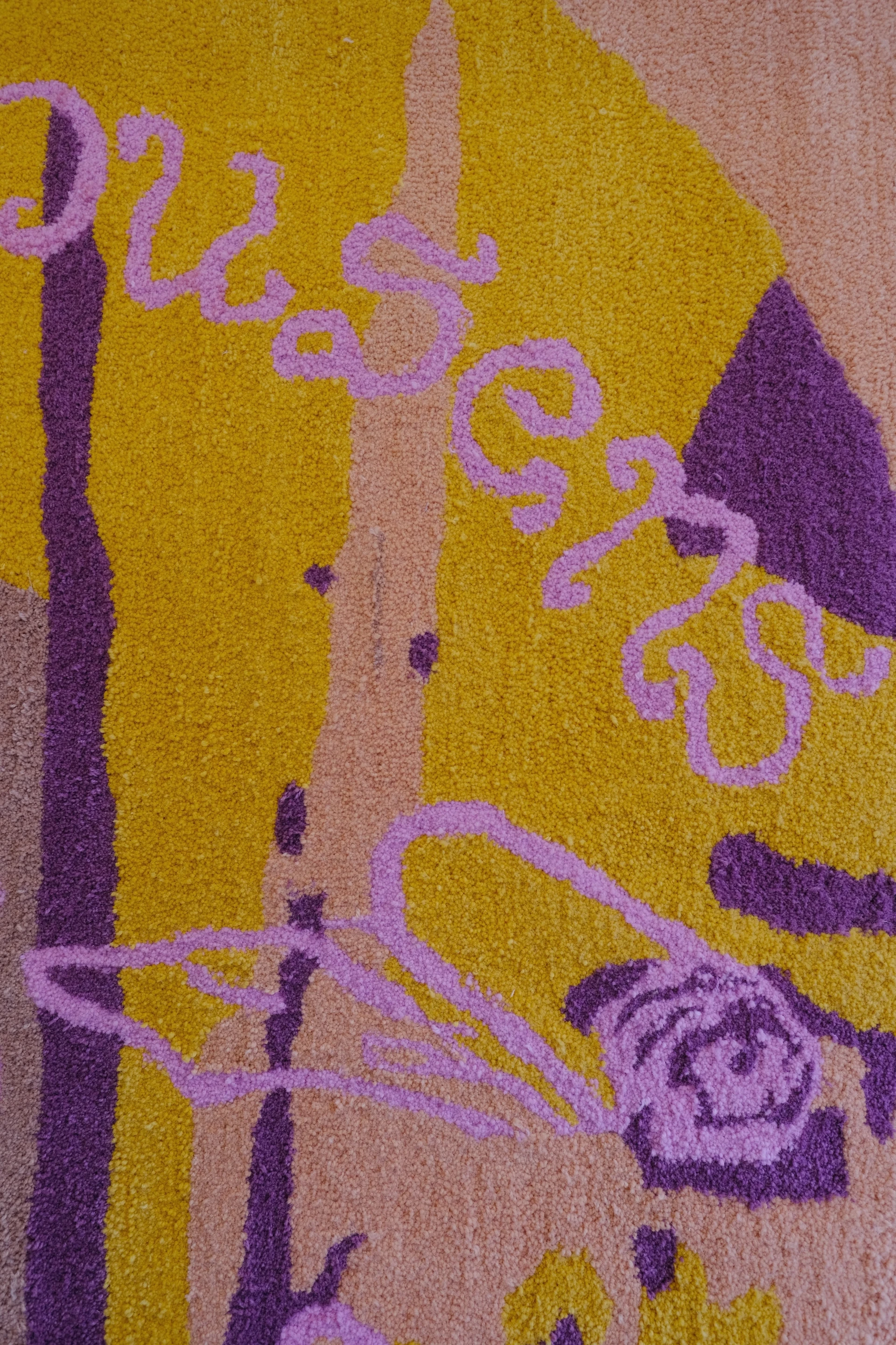 Pink tufted lettering and a flower motif cross ochre, salmon and plum wool, showing the texture and depth of the cut pile.