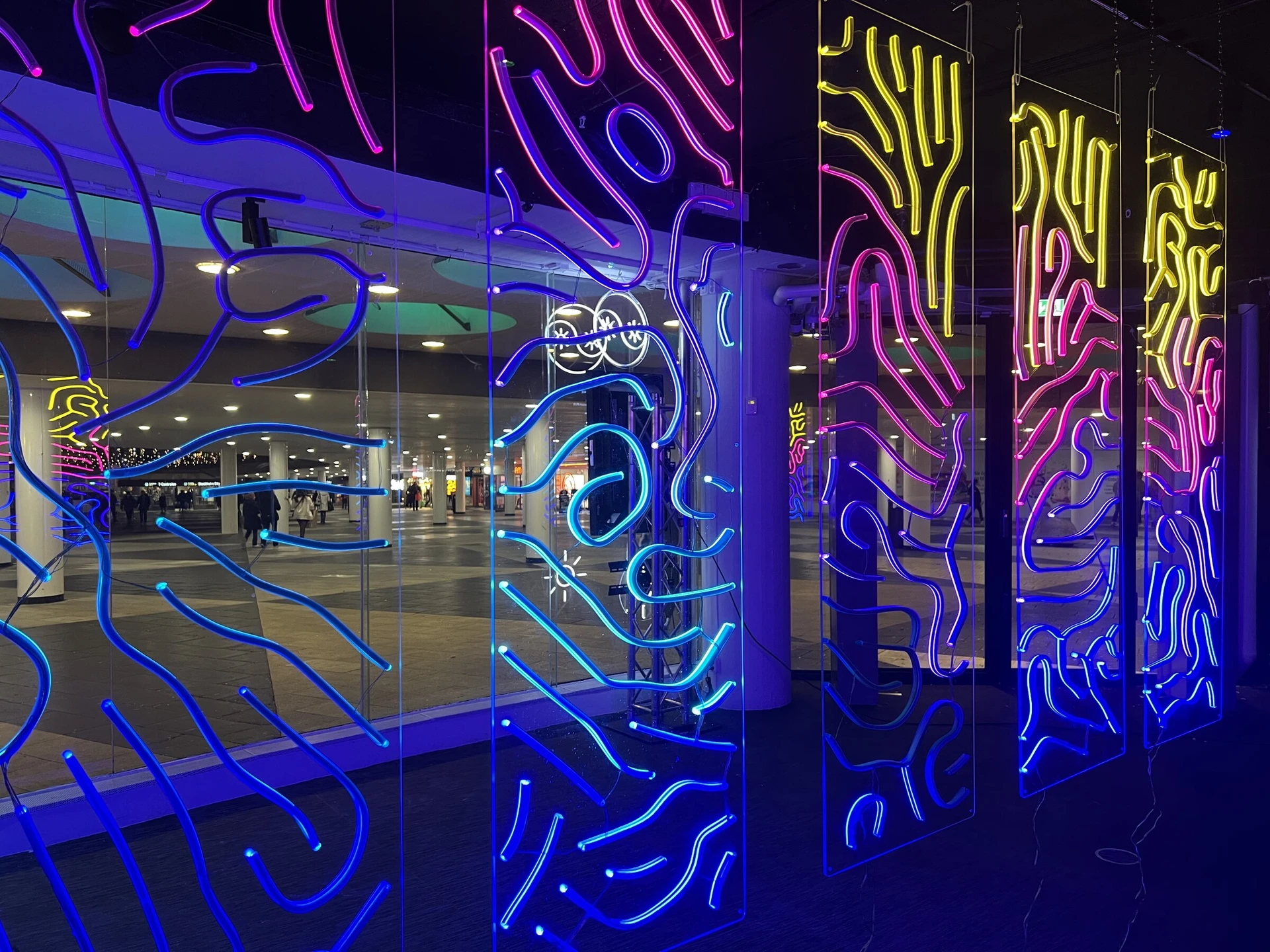 The signs hang inside the glass front, with the lit passage at Plattan visible through them.
