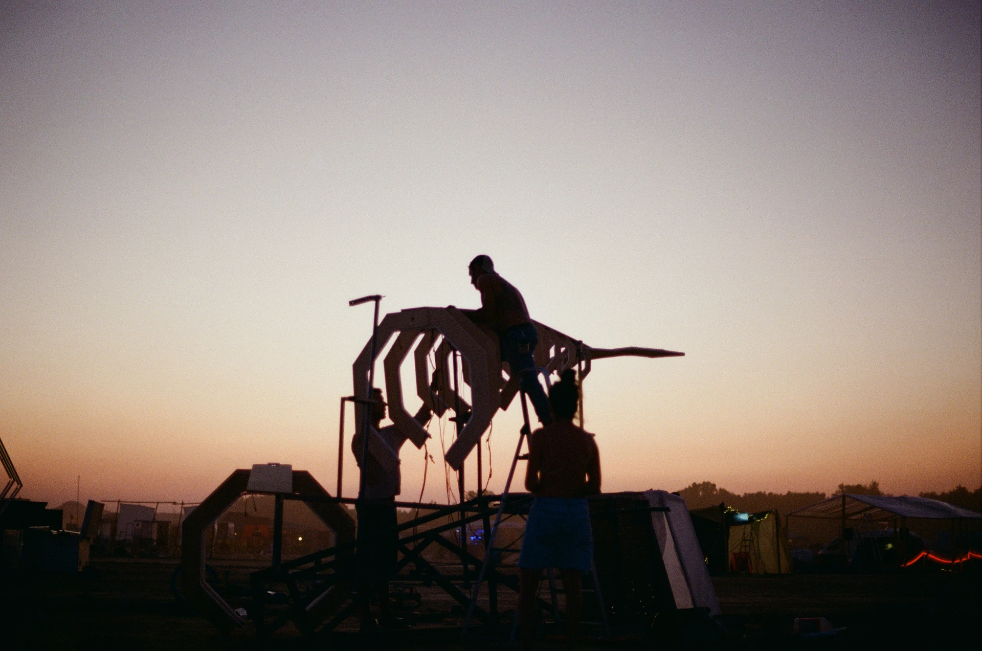 A film photograph of the crew lifting and fitting the whale's body onto its frame as the desert sky turns orange.