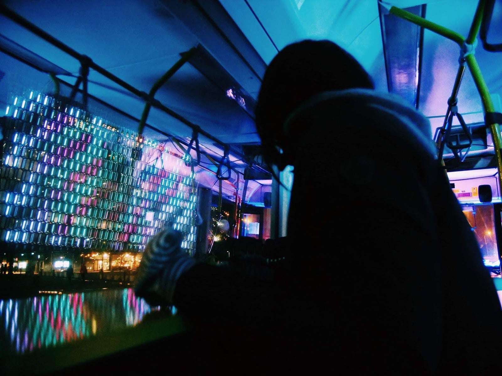 A visitor watches colourful patterns illuminate the glass panels of Harpa Concert Hall.