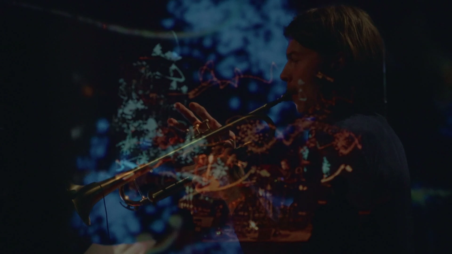 The saxophonist in profile with the projected score falling across him, pale blue marks over his face and horn.