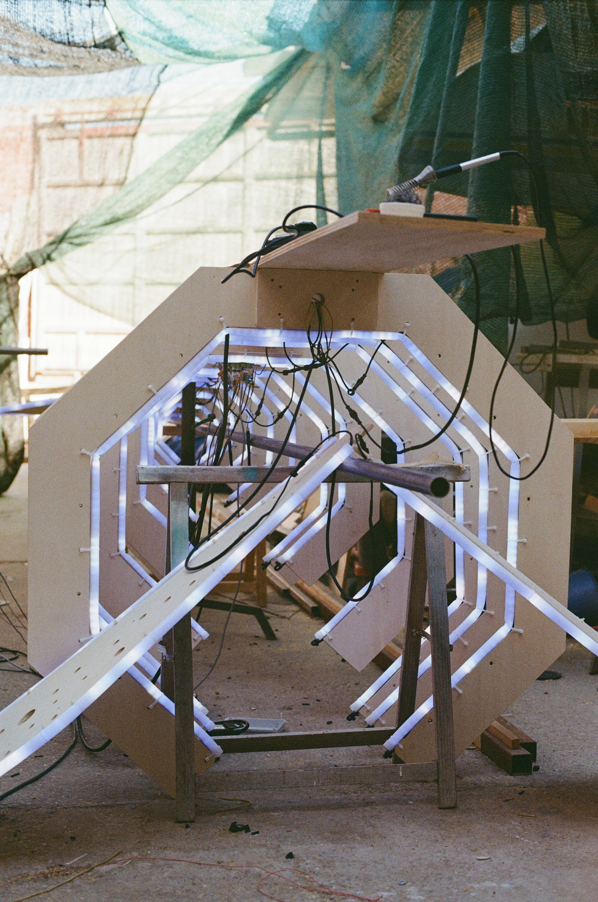 A film photograph looking through the whale's ribs during a lighting test, with white LED tubes and their wiring visible.