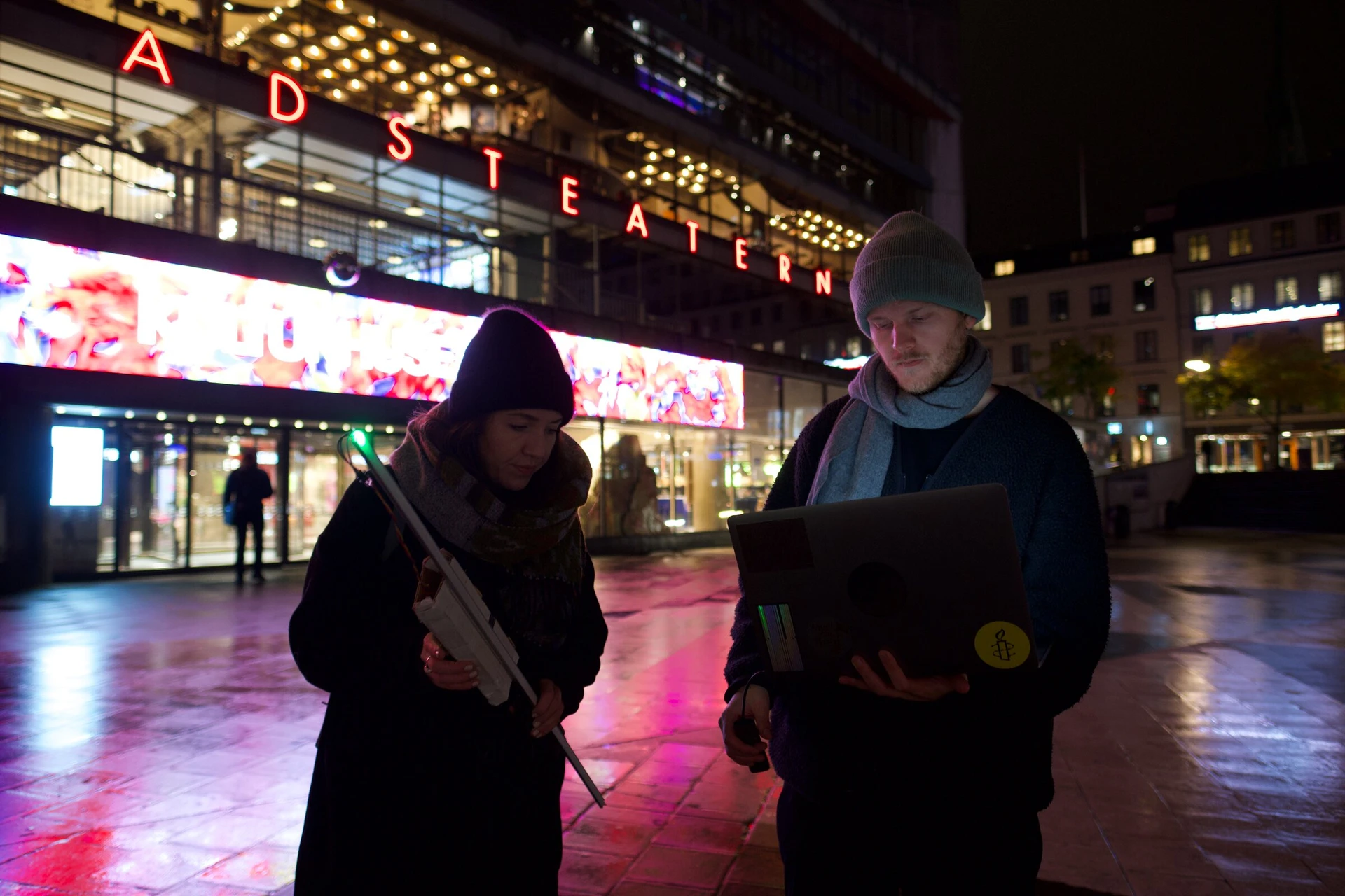 Outside Kulturhuset Stadsteatern, one person holds the LED stick while another checks a laptop.