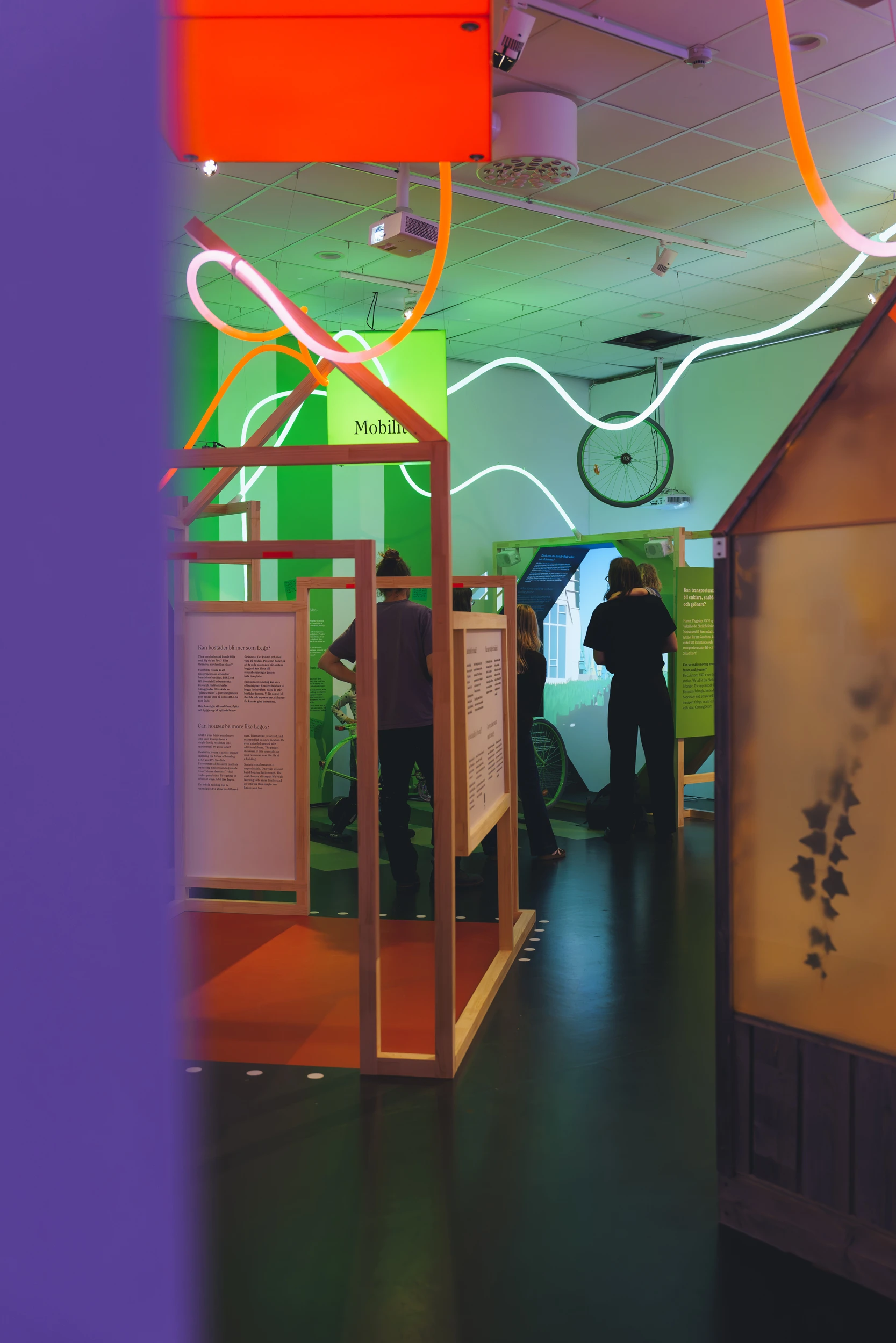 Glowing white lines loop above a narrow passage between an orange display frame and translucent panels.